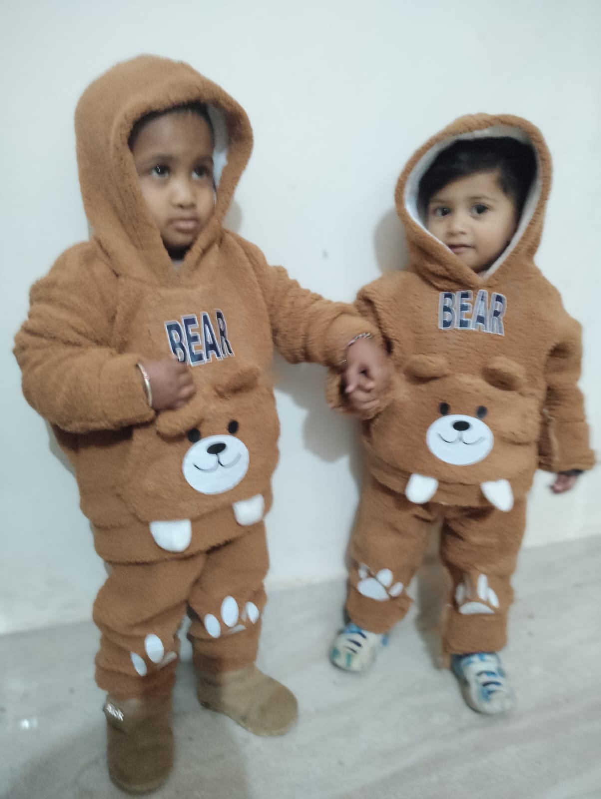 Two toddlers in bear suits holding hands
